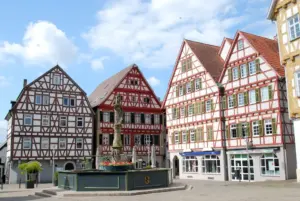 Fachwerkhäuser mit rotem Fachwerk und grünen Fensterläden am Marktbrunnen in der Leonberger Altstadt, Immobilien verkaufen mit Makler Imo Meyer