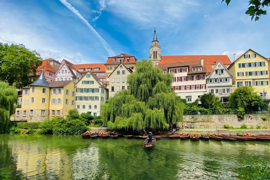 Blick auf die bunte Tübinger Altstadt mit Fachwerkhäusern, Stiftskirche und Stocherkähnen am Neckarufer im Sommer